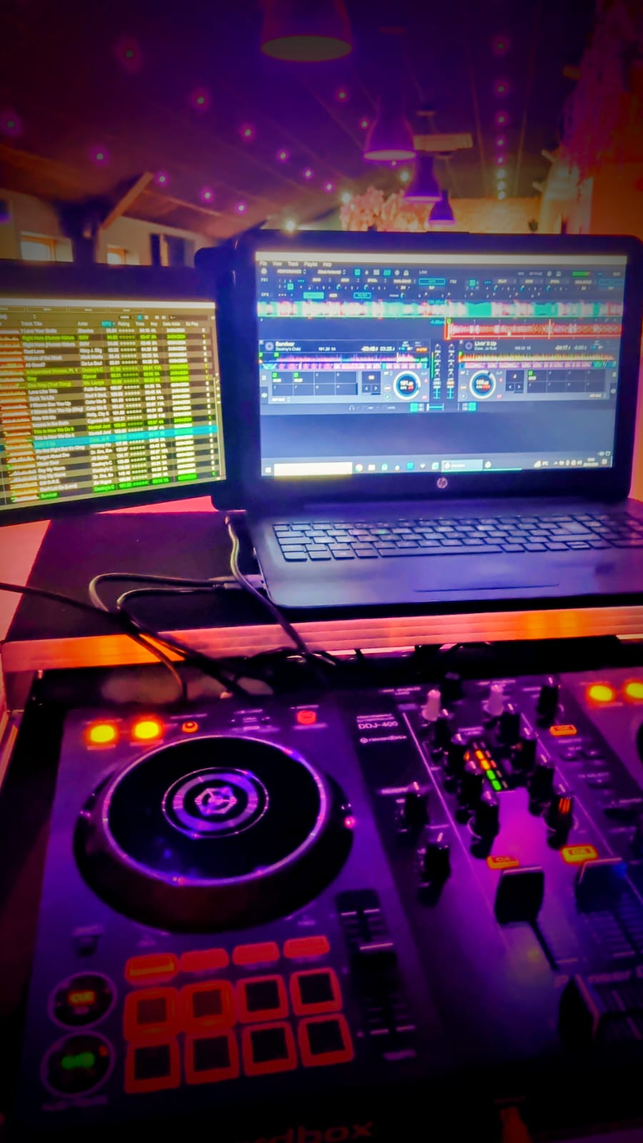 Simon's DJ setup — Pioneer DDJ controller and laptop glowing under venue lights
