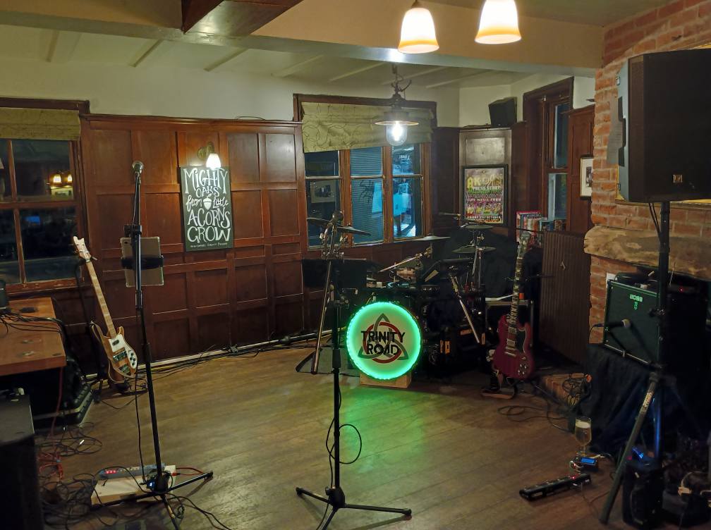 Trinity Road stage setup at a pub with illuminated Trinity Road drum logo